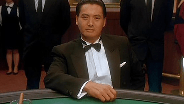 Scene from the film God of Gamblers (1989), with actor Chow Yun Fat as Ko Chun, wearing a black suit and his arm on the casino table.